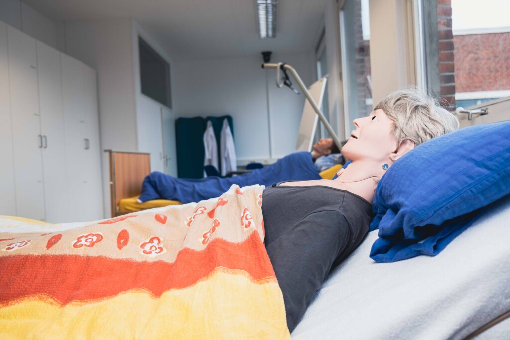 Auf dem Bild sieht man zwei Pflegepuppen, die in Betten liegen. Das Foto entstand im digitalen Skillslab der ibs Pflegeschule Bremen.
