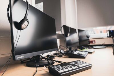 Auf dem Bild sieht man drei Computer-Bildschirme mit Headsets und einer Tastatur. Das Foto entstand im digitalen Skillslab der ibs Pflegeschule Bremen.